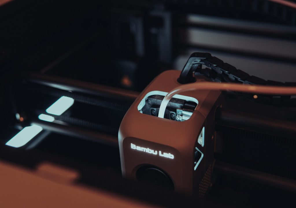 Detailed view of a 3D printer mechanism in a dark setting, highlighting technology.